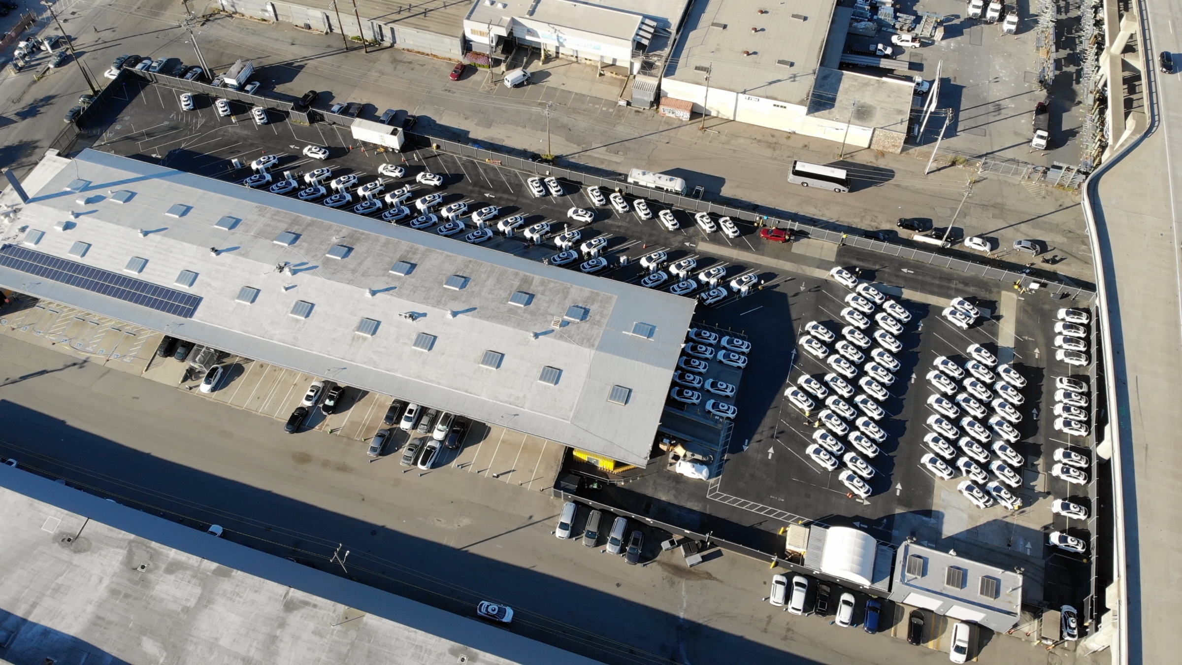 A photograph of a parking lot with white autonomous vehicles and charging equipment