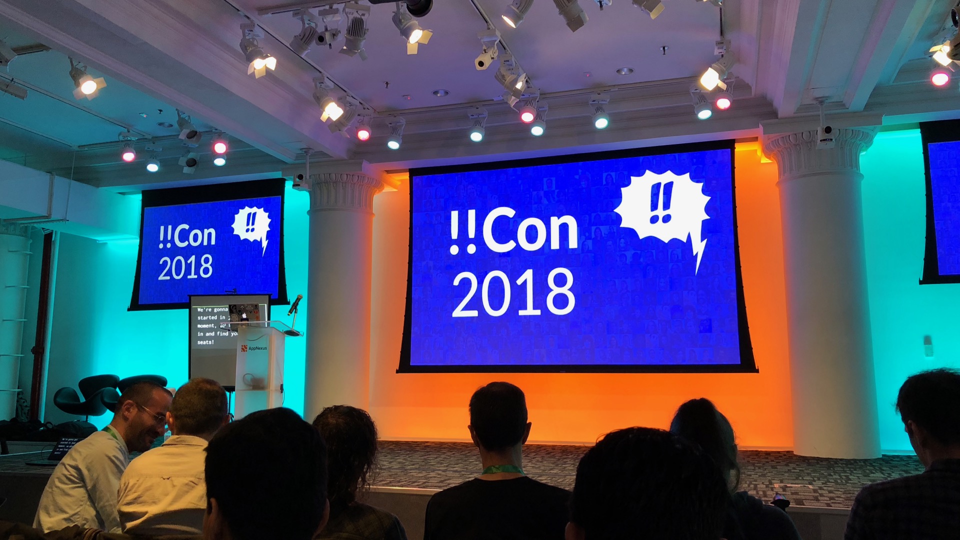 A stage with a projector showing the name of the conference on a blue background