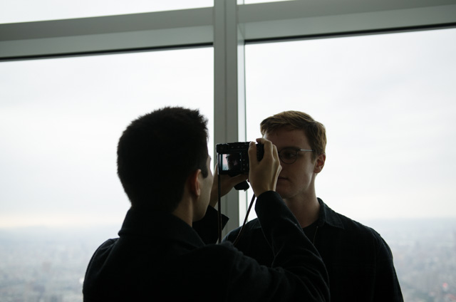The same photo, but darker. The city skyline is now visible, but the subjects' faces are dark.
