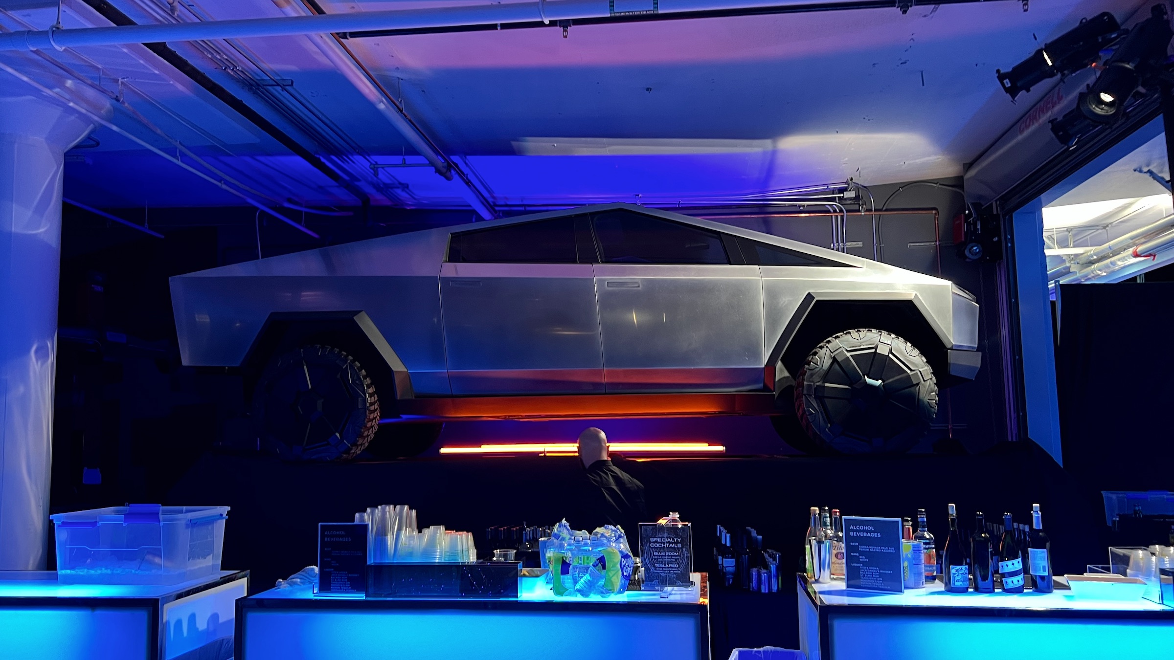 A Tesla Cybertruck suspended over a bar and bartender.